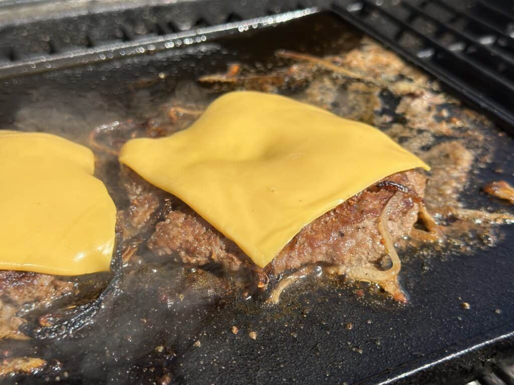 cheeseburger cooking on a grill.
