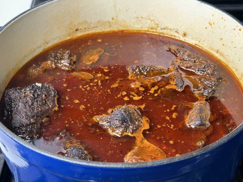 smoked beef birria braising in a dutch oven