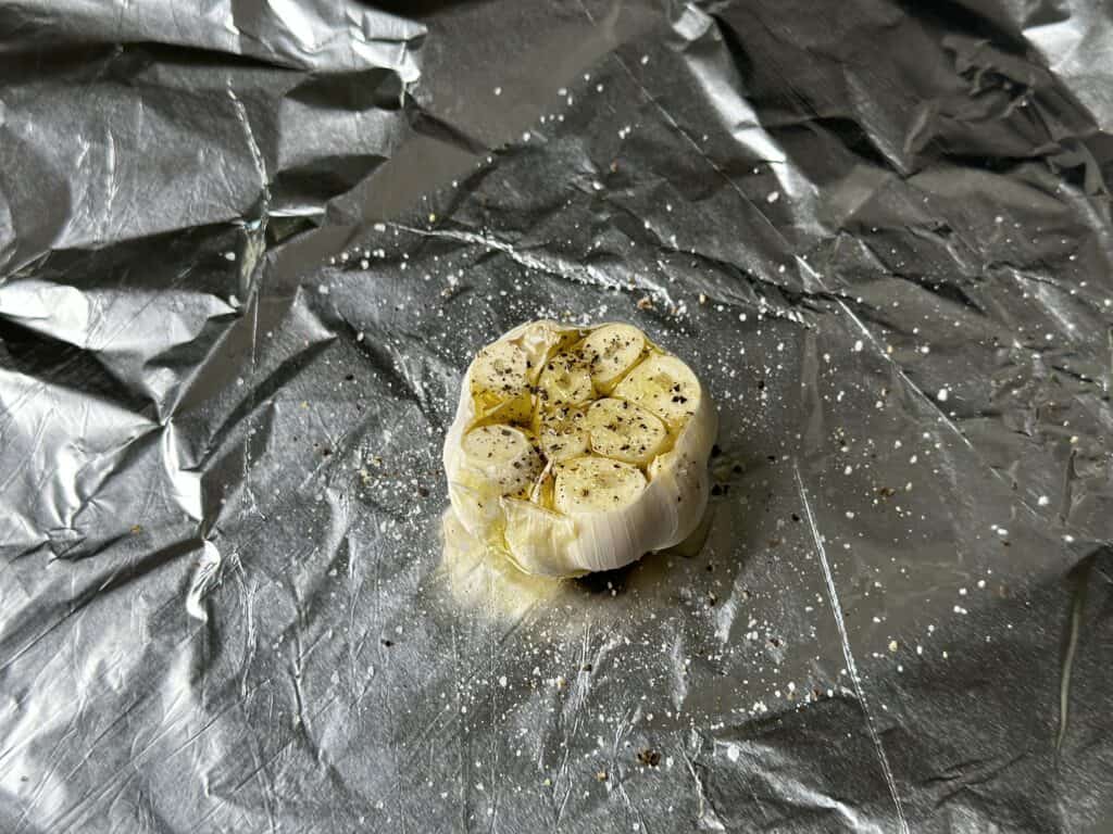 head of garlic on aluminum foil.
