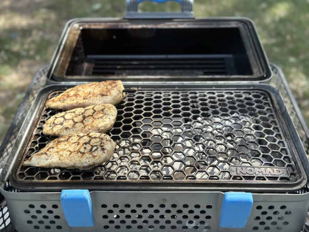 Chicken being grilled over charcoal.