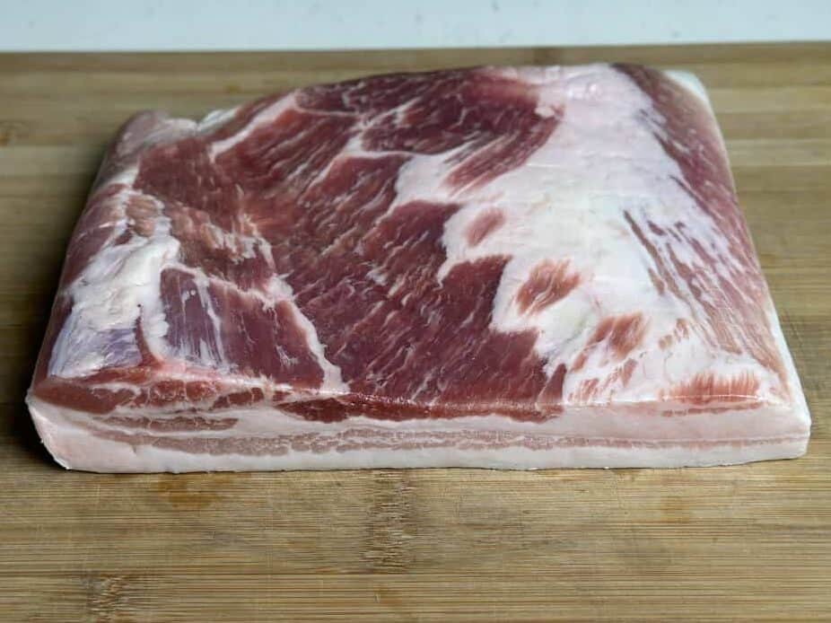 slab of pork belly on a cutting board.