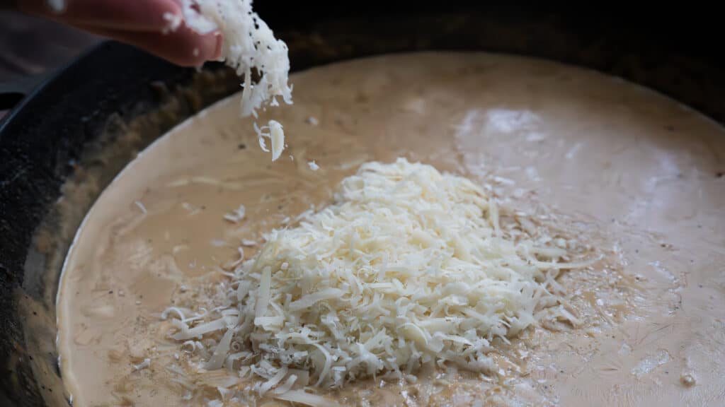 parmesan cheese added to a skillet 