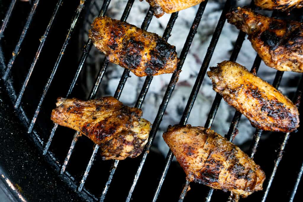 chicken wings being grilled over charcoal