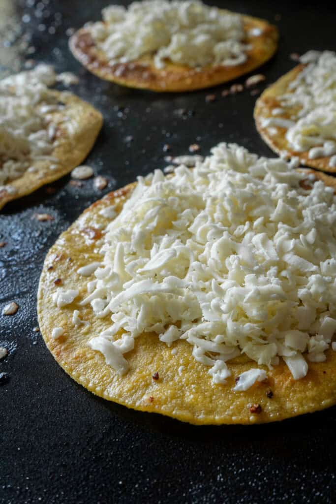 yellow corn tortillas with Oaxaca cheese on a griddle.
