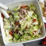 A salad with meat, lettuce and tomatoes in a white bowl.