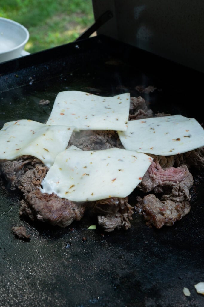 Cheesesteak cooking on a griddle.