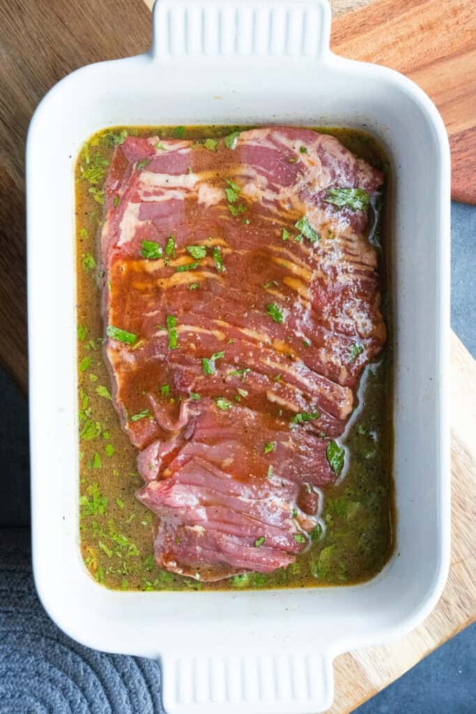 Skirt steak marinating in a dish.