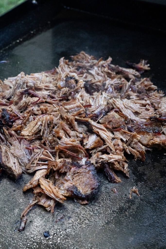 Smoked brisket cooking on a griddle.