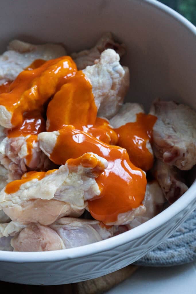 Chicken wings being seasoned.