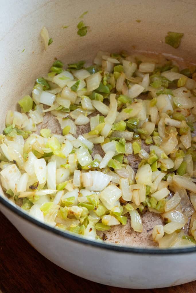 green peppers and onions cooking in a dutch oven.