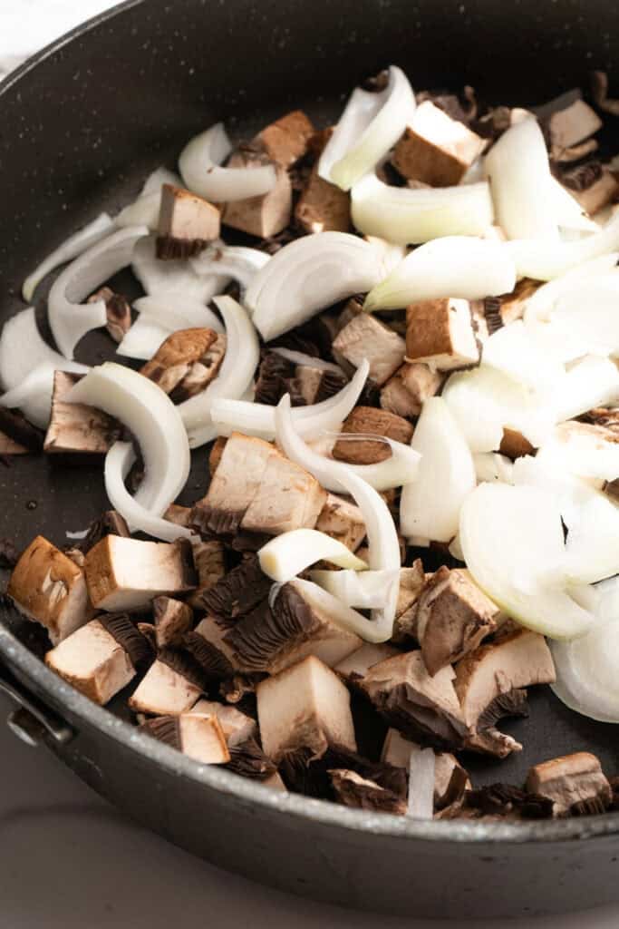mushrooms and onions cooking in a skillet.