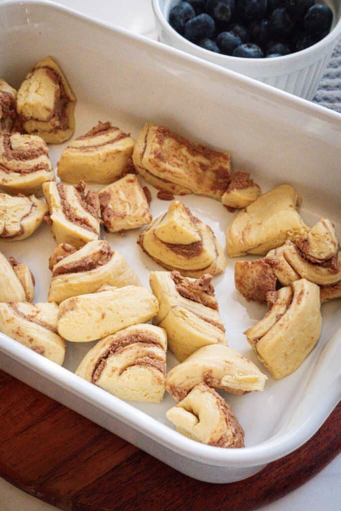 Cut up cinnamon rolls in a baking dish.