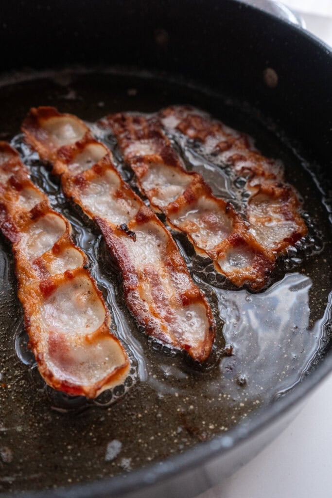 Bacon frying in a skillet.