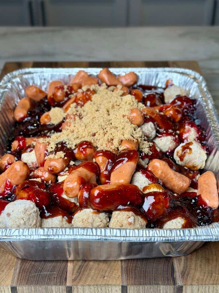 ingredients in a foil pan for lil smokies and meatballs.
