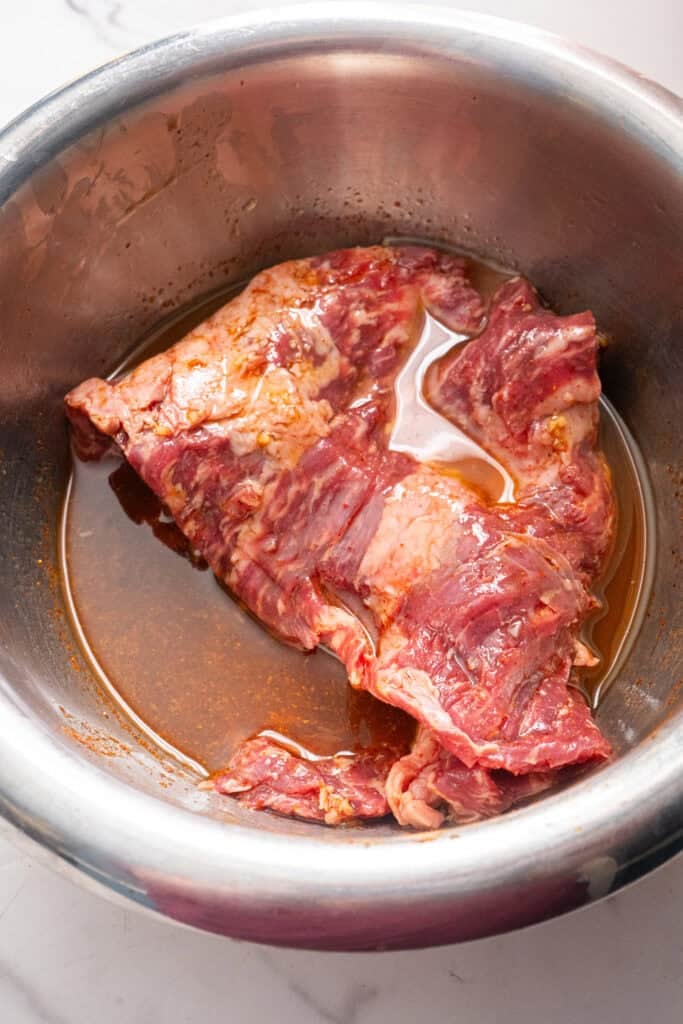 skirt steak marinating in a bowl.