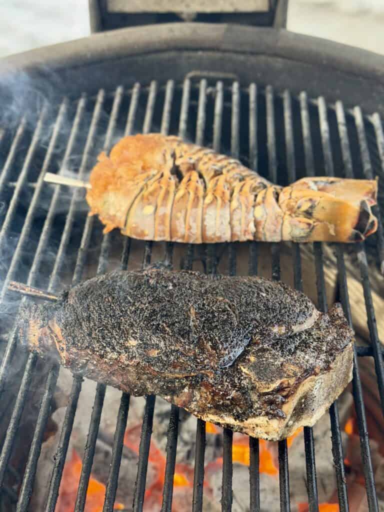Steak and Lobster being grilled over charcoal.