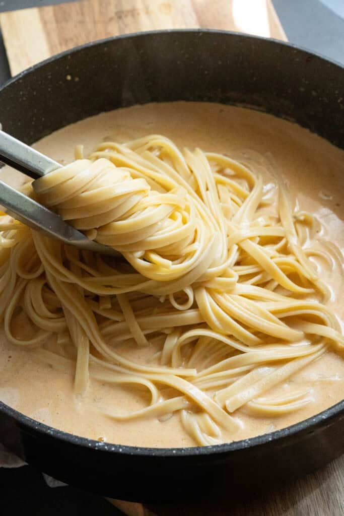Adding noodles in sauce.