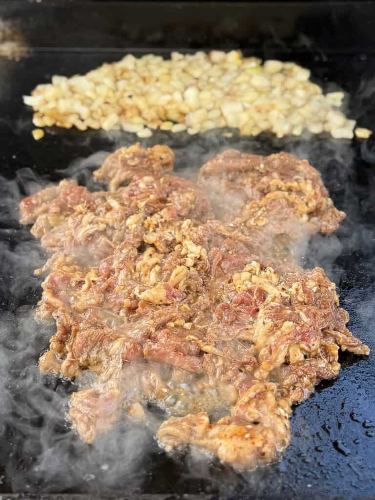 Shaved ribeye cooking on a griddle.
