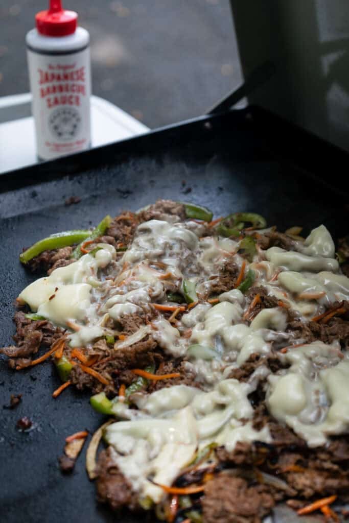 Beef and cheese cooking on grill.