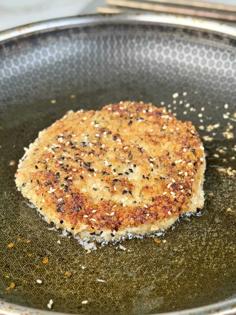 Browned Chicken patty in pan.
