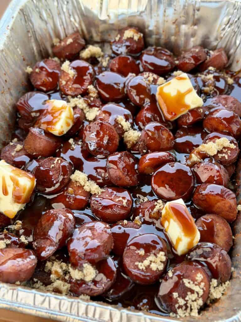Sausage with BBQ Sauce and Butter in Pan on Smoker.