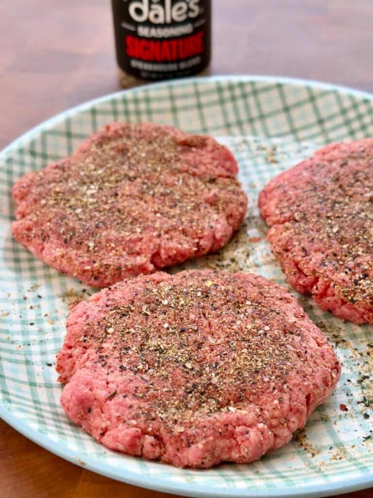 Seasoned burgers on plate.