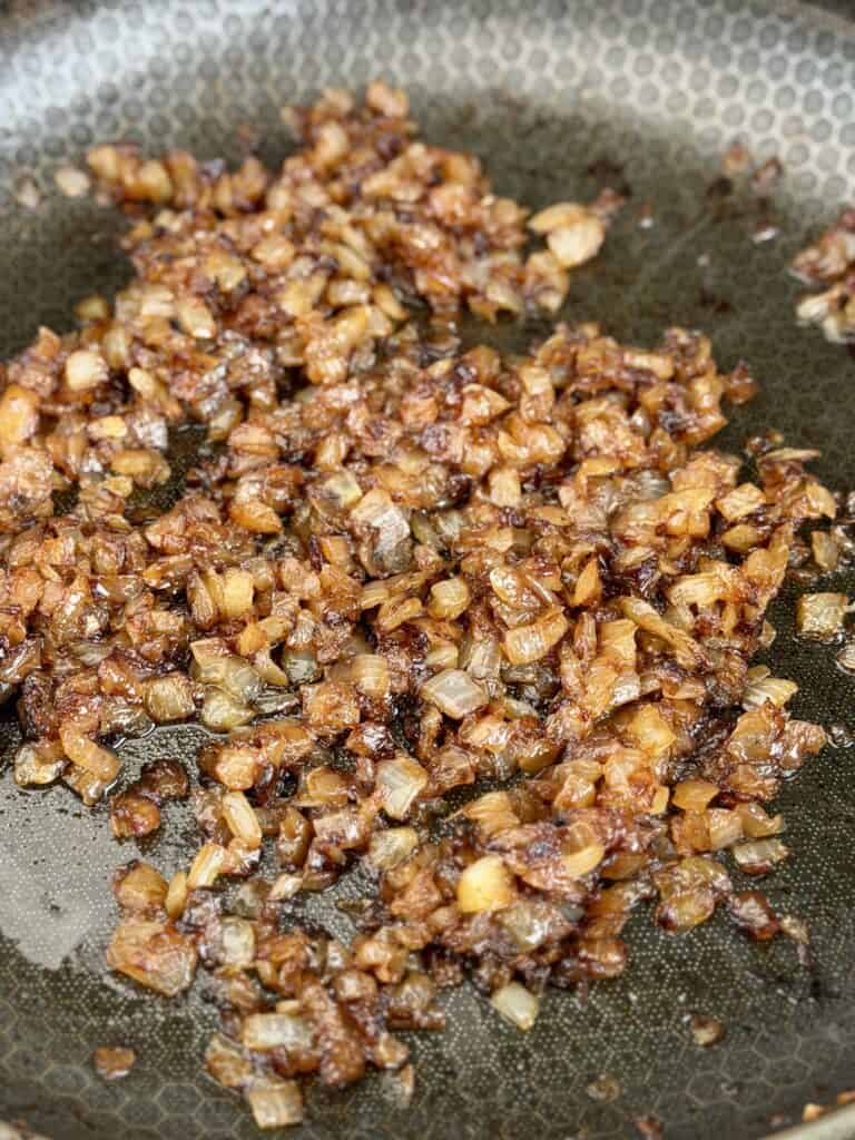 Onions cooking in pan for Bacon Cheeseburger Pasta Salad.