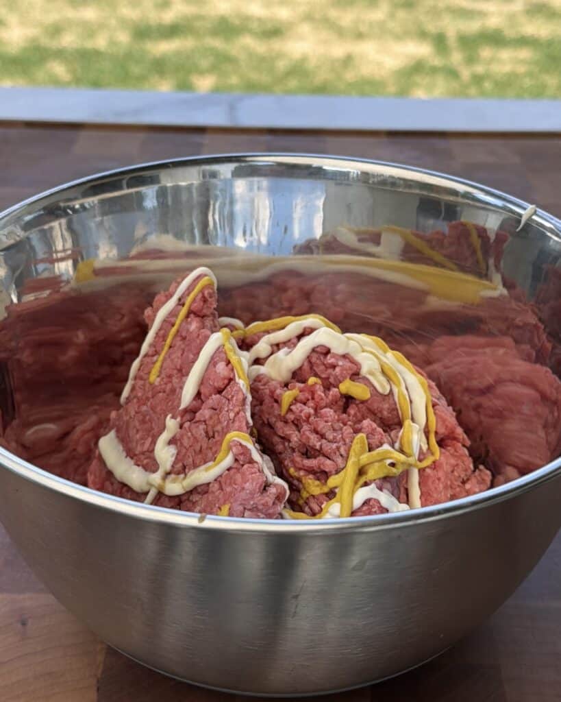 Hamburger in bowl with mayo and mustard.