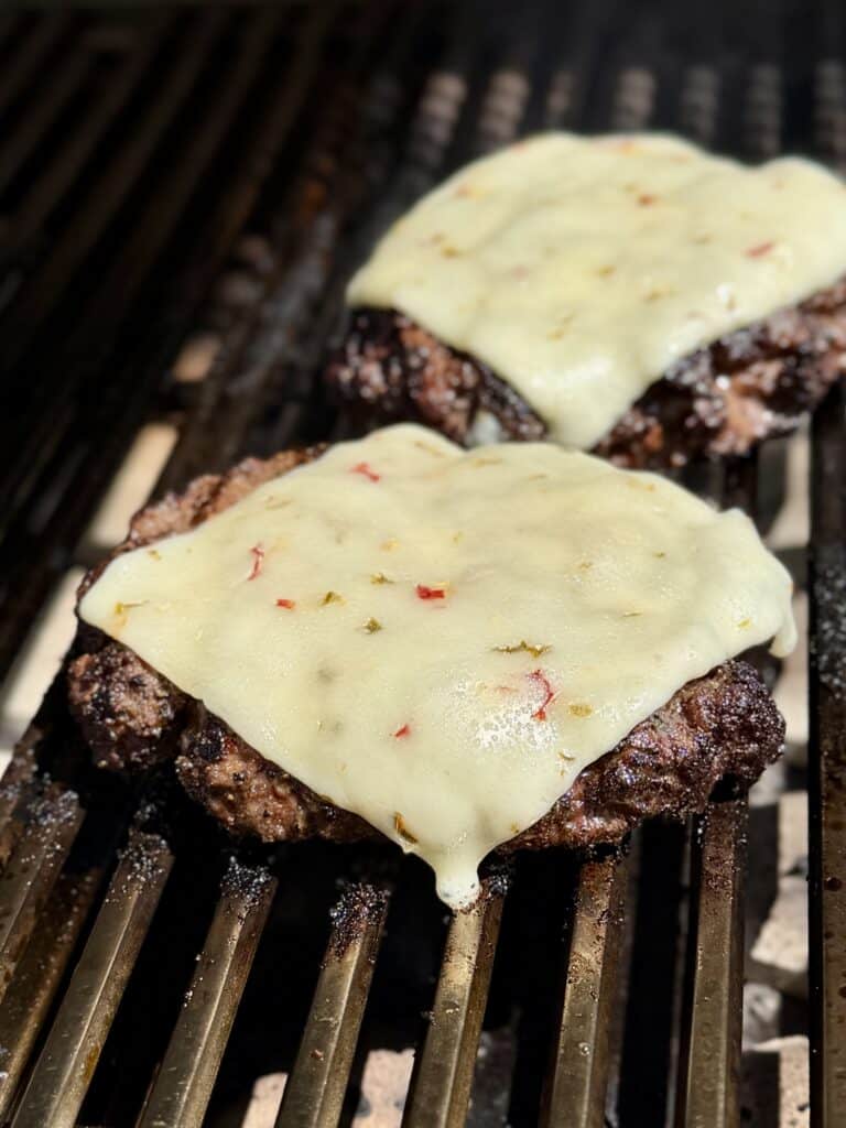 Cheese on Burgers on Grill.