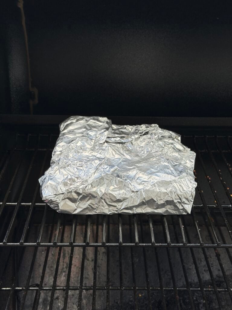 Meat wrapped in foil on smoker.