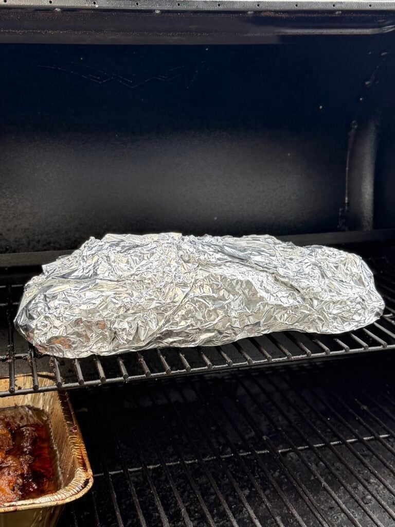 Meat in foil on smoker.