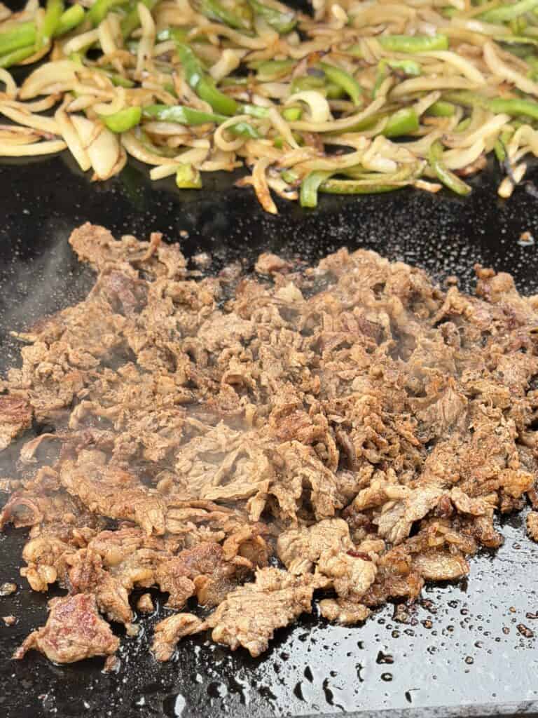Cheesesteak meat cooking on griddle.