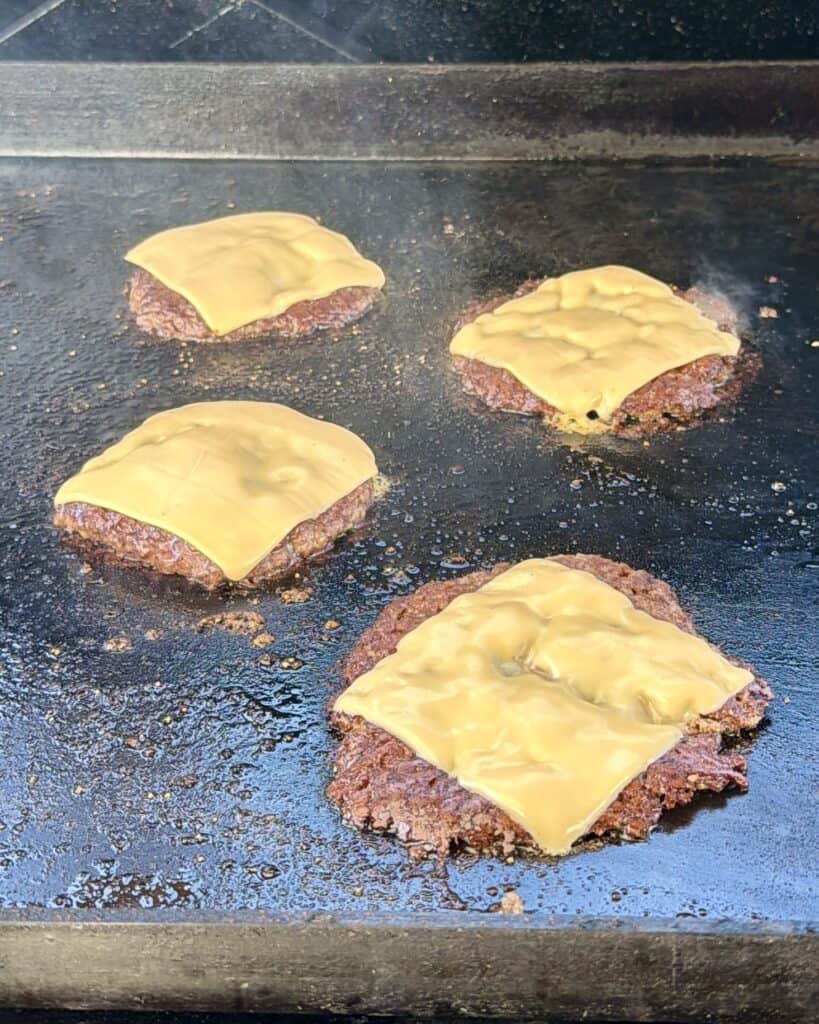 Cheese on burger on griddle.