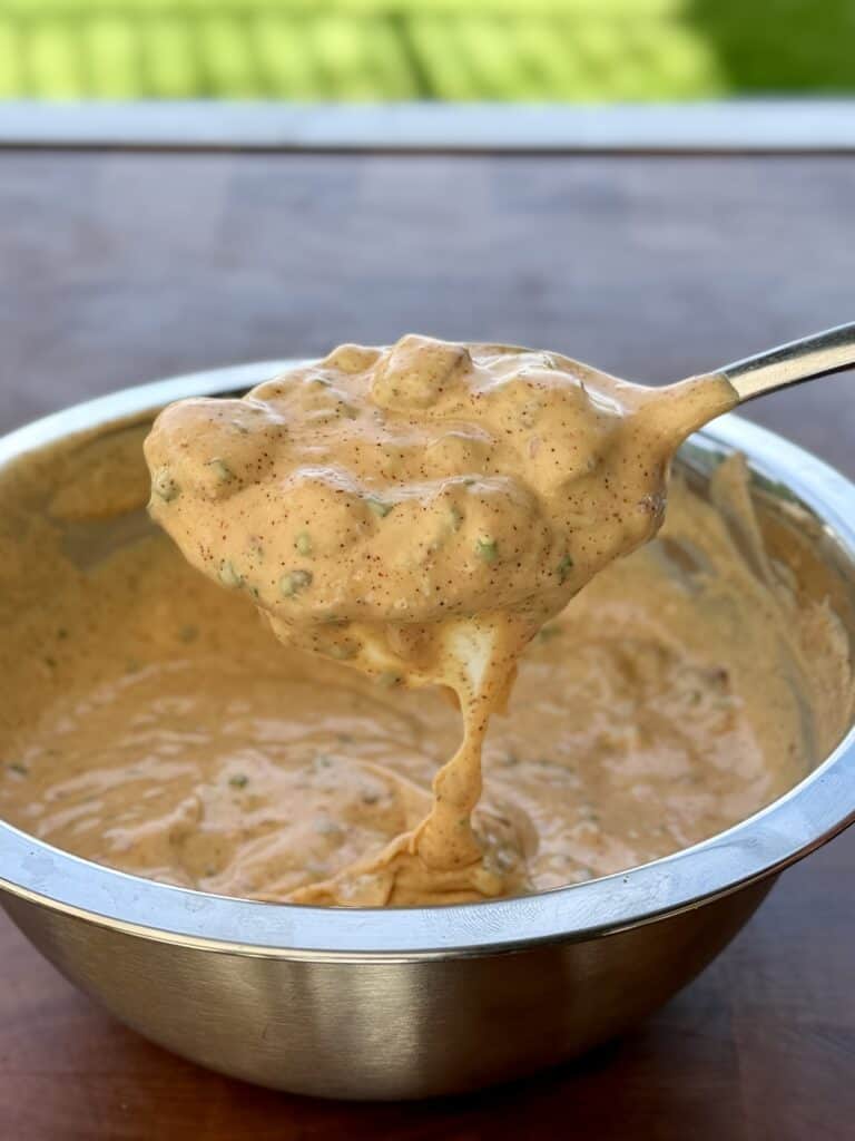 Spoon of sauce over bowl.