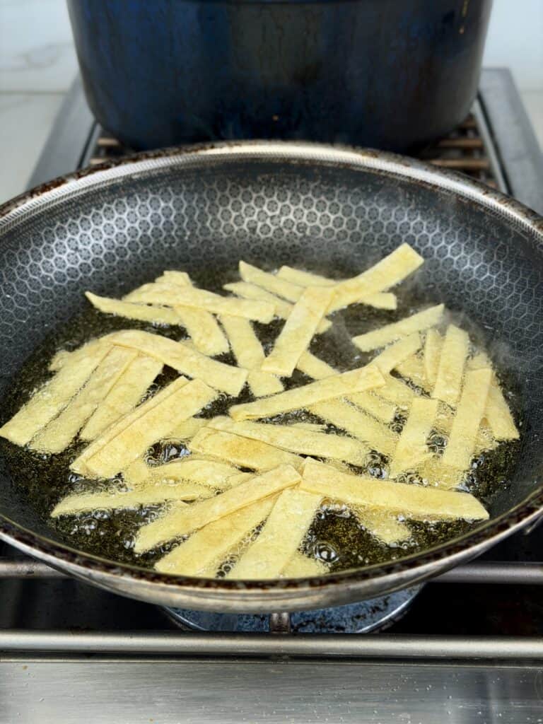 Deep frying tortilla strips in pan.