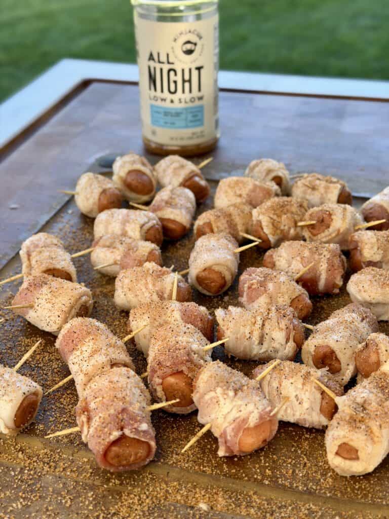 Lil smokies wrapped with bacon on cutting board.