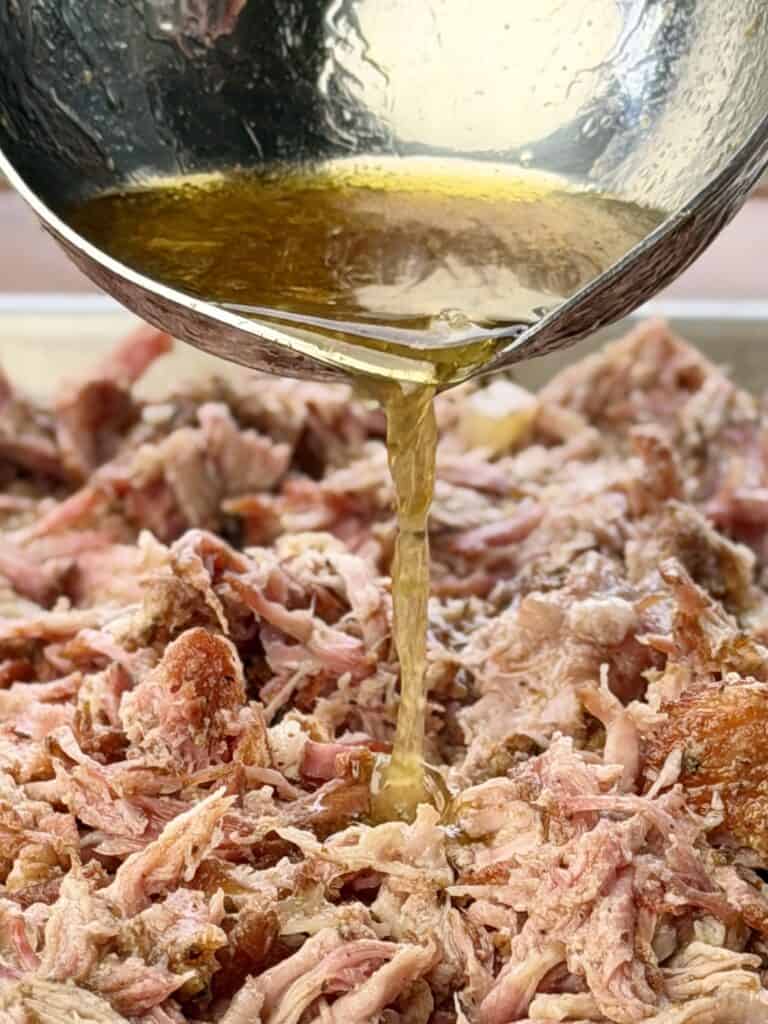 Pork with juice in ladle.